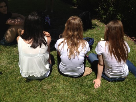 Students who are wearing white enjoy eating lunch in the sun.