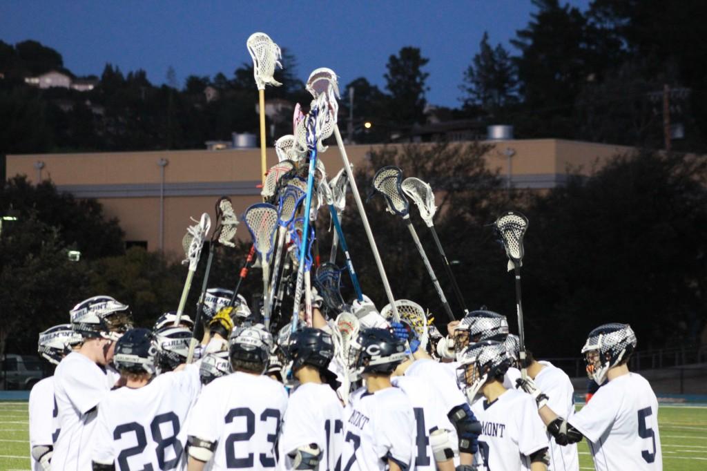 The boys varsity lacrosse team raises their sticks during a team chant.