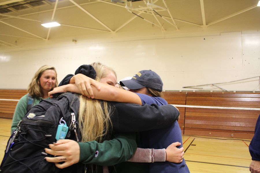 Seniors Katelyn McGrath and Lauren Racioppi wrap Cadona in a celebratory group hug. 