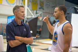 Coach Steve Kerr discussing strategy with his superstar Stephen Curry