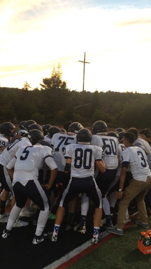 Carlmont Scots huddle together before they charge onto the field.