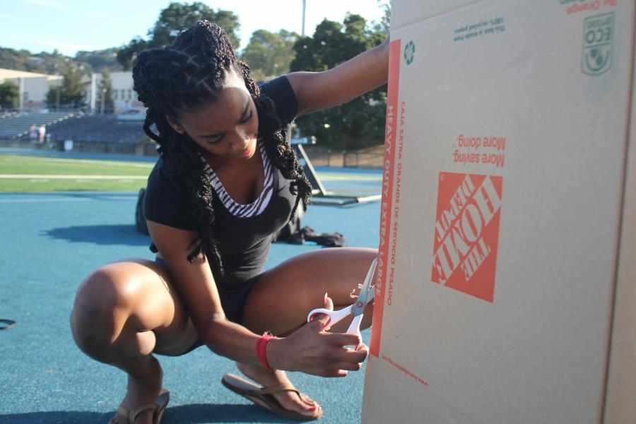 Senior Camille Duvalsaint cuts through cardboard to set up an arch for the senior float.