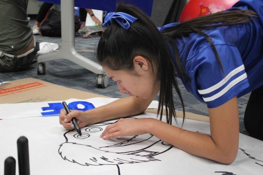 Junior Miranda Wong traces her drawing of Dug to enhance the lines. 