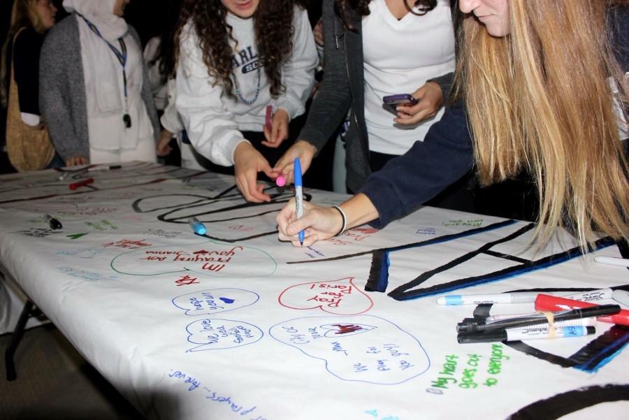Students sign a banner in remembrance of the lives that were lost in the attacks in Paris.