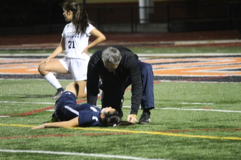 Coach Scott Pendleton checks freshman Kaylee Leong after she was injured by a slide tackle made by one of the Wildcats.
