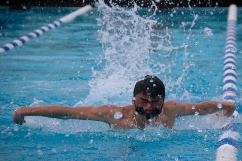 Freshman Nathaniel Pon veers into the lane line as he struggles to swim with his goggles slipping off.