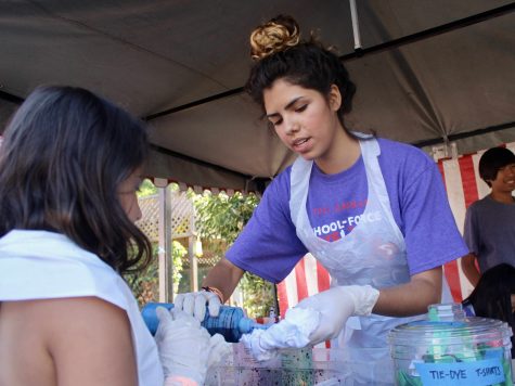 A young girl learns how to tie dye with the help of junior Sofia Perez.