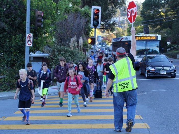 Local crossing guard, Edward Henken, helps San Carlos students safely cross the street to school.