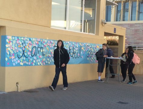 Students add to and walk by a mural that reads I am thankful for, which serves as a Thanksgiving decoration, kicking off the holiday season.