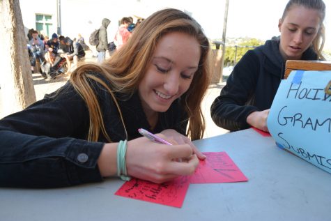 Emma Vanoncini, a junior, writes a handwritten note on a holiday gram for her friend.