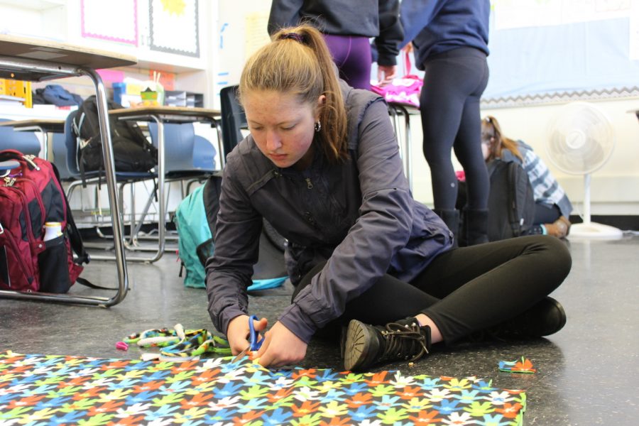Sophomore Katia Deynegay focuses while she cuts the fringes of a Kozy Kids blanket.