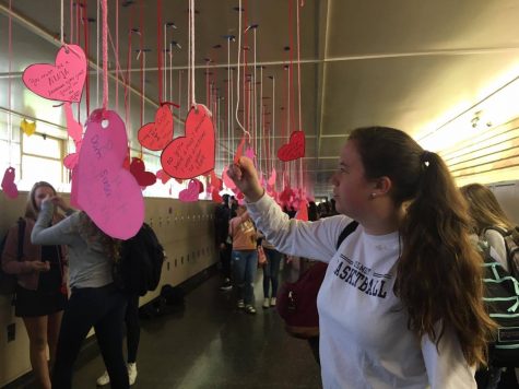 Chloe Kelly, a junior, reads the Valentines Day notes in the hallway.