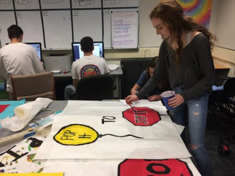Maddie Standlee, a member of the Human Relations Commission, works on posters to spread awareness for Gender Equality Week. She paints a stop sign to advertise for the Erase the Negative day in which one activity encourages students to pop balloons with common sexist sayings to show their opposition. 
