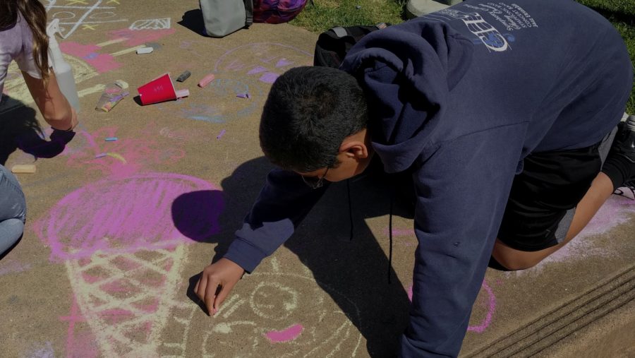 Sophomore Joshua Mathew draws a happy face during the Chalk for Happiness event..