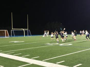 Girls varsity lacrosse works together to achieve victory.