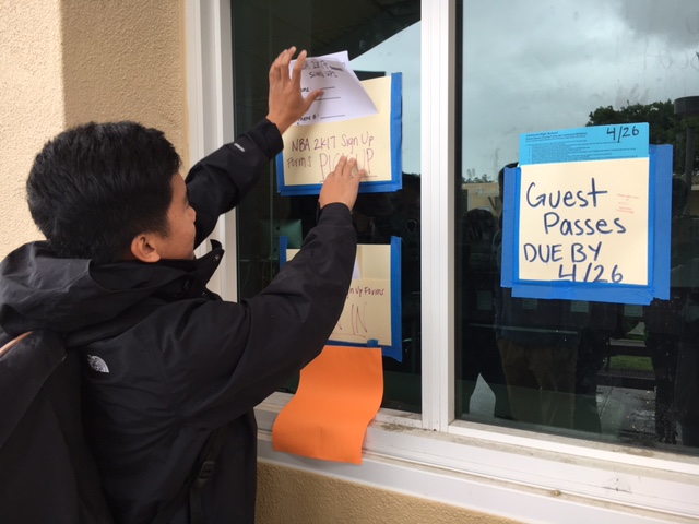 Liam Jocson, ASB president, drops blank sign-up sheets in a folder outside the ASB room.