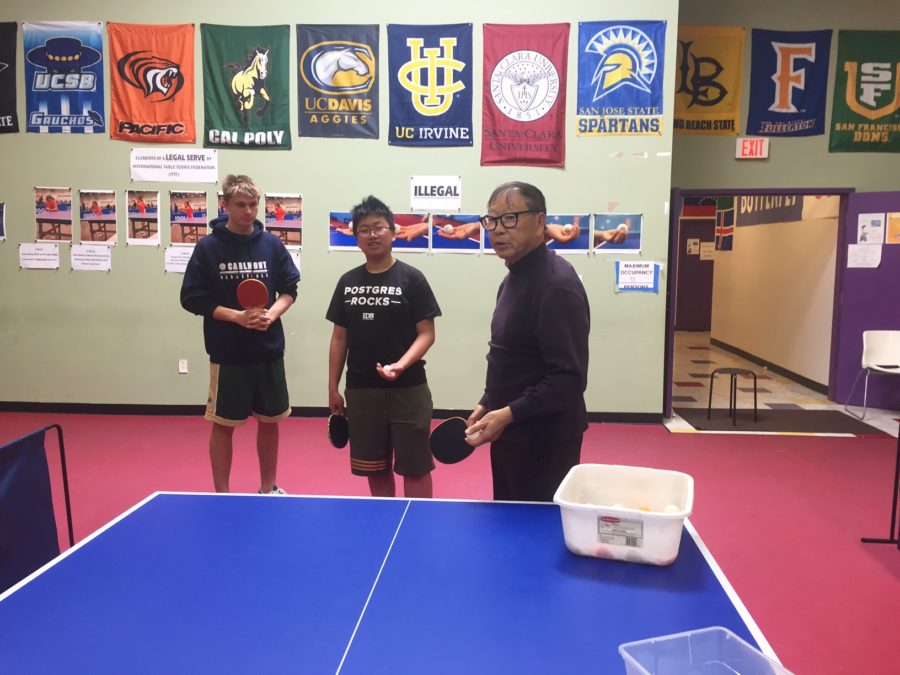 Instructor Lau explains to Albert Li and William Jessen how to serve the ball at the start of a game.