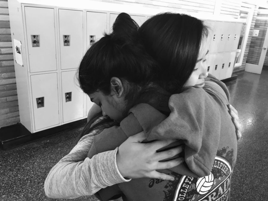 Friends share a hug in the hallway in the midst of school stress.