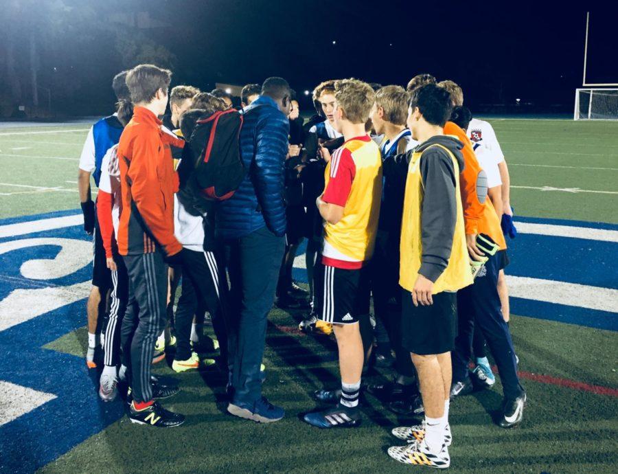 The Carlmont JV Boys soccer team huddles up as their practice session ends. Altogether, they  chant in unison over the field logo and cheer on school spirit. 