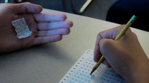 A student uses crib notes to cheat on a multiple choice exam. The use of crib notes is a common form of cheating.