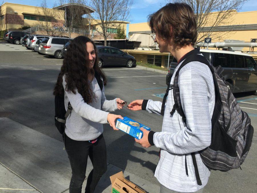 Luke Hendrickson, a sophomore, buys a box of Trefoils from Ana Alvarez-Rutz, a Girl Scout.