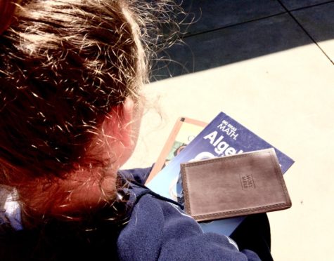 A student holds her textbooks along with her Bible as she prepares for school.