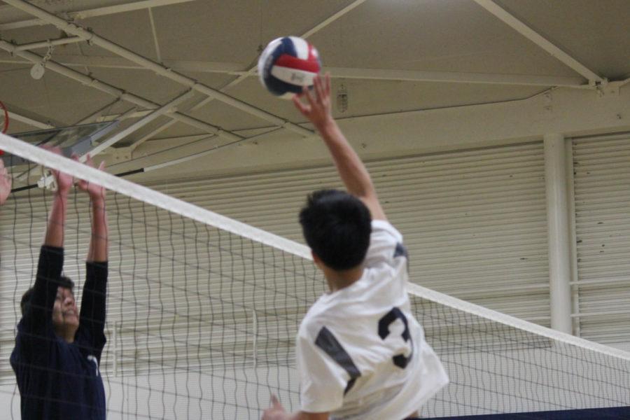 Freshman Justin Wong hits the ball over the net, getting past the Eagles blocker.