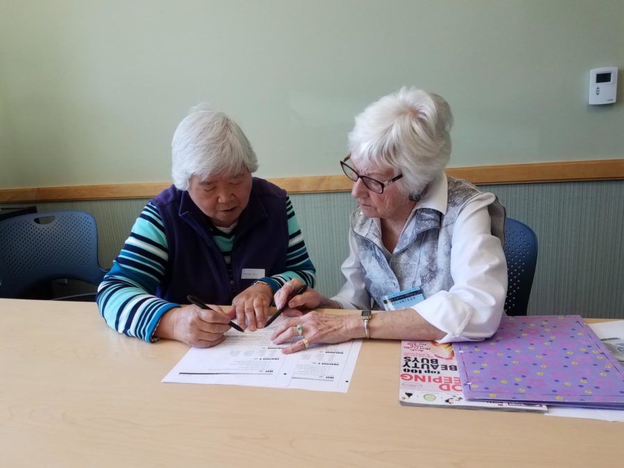 A volunteer works with a club participant on phrases associated with grocery shopping.
