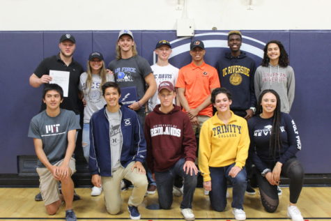 Seniors who signed to college sports teams take a picture during the signing ceremony.