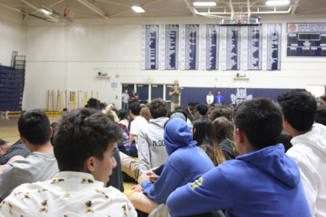 students seated on gym floor