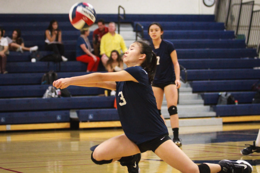Claire Tseng, a freshman, digs up the ball for her team.