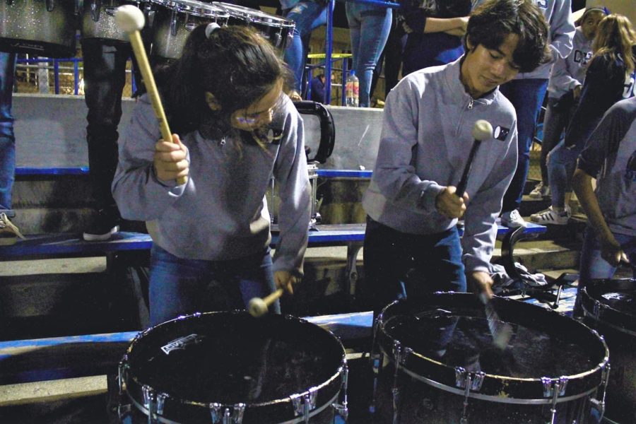 Juniors Isabel Coughlin and Niko Haller play the bass drums at a football game. 