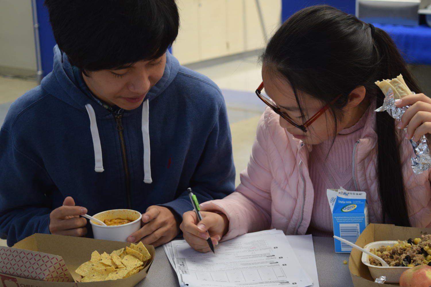 Melody Liu, a junior, helps Lou Bao, a senior, with his homework at lunch. 
