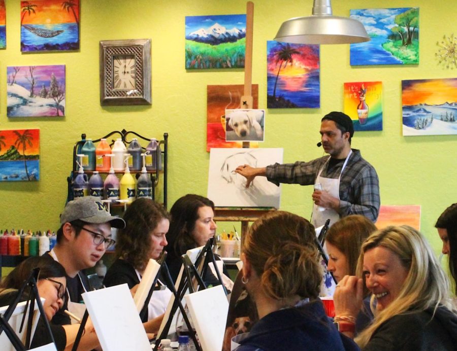 Pet-owners listen to the instructor at Bottle and Bottega to paint portraits of their pets.