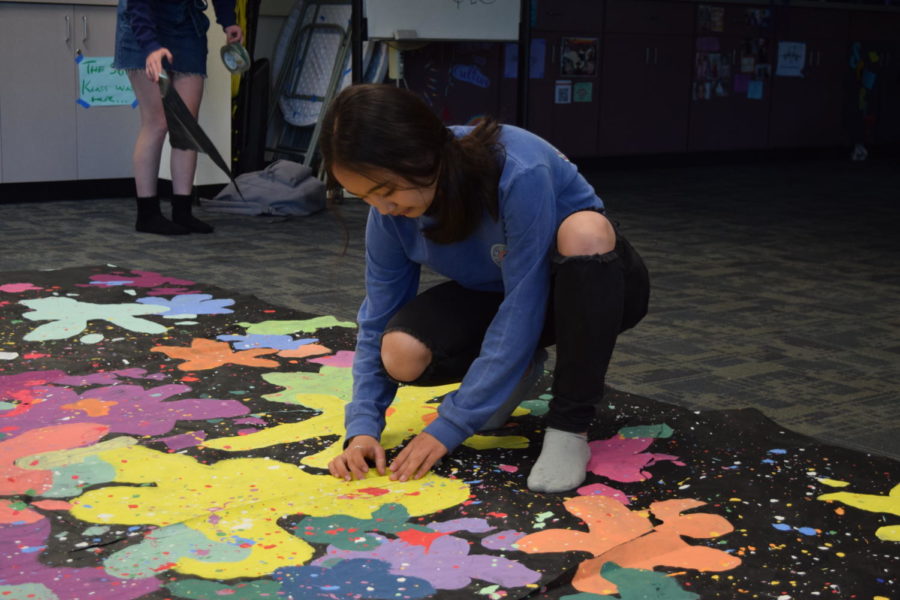 Rachel Gu, a senior and supervisor of activities in publicity, tapes up a damaged banner. 