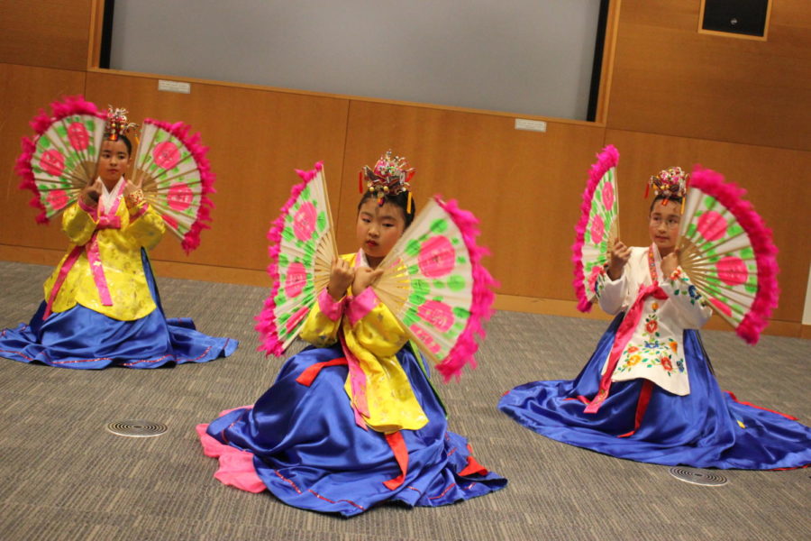 Korean dancers wave brightly colored fans decorated with flowers. 