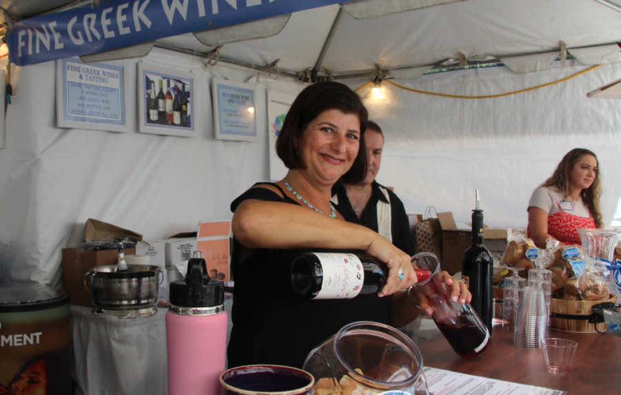 On opening day, one of the women working at the wine tasting booth pours a customer a bottle of wine.