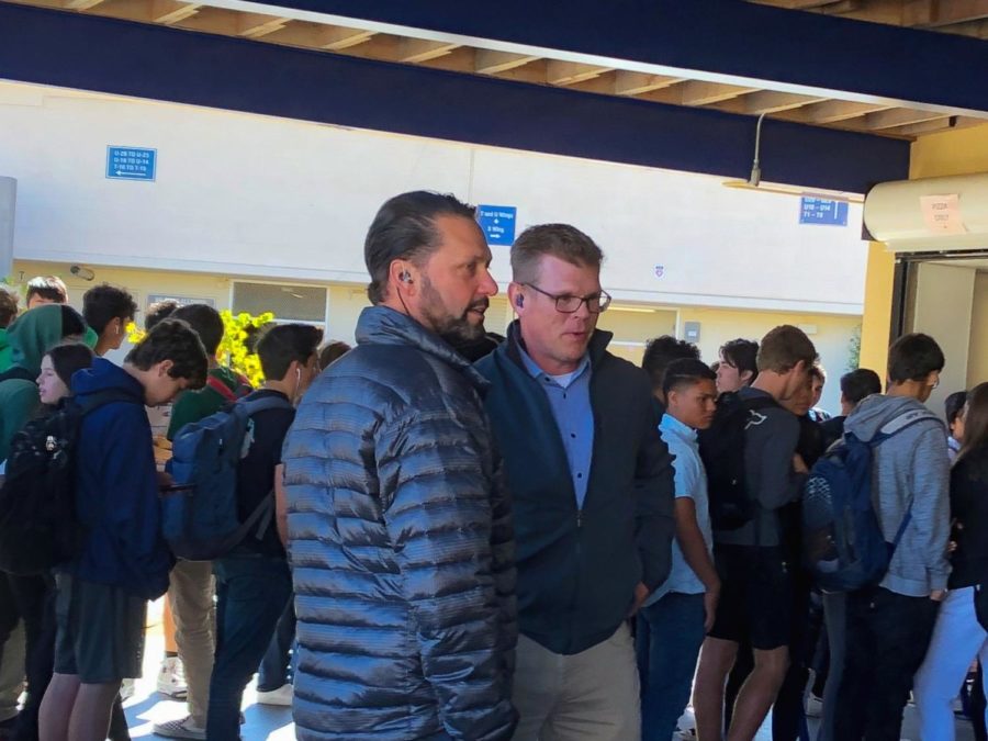 Grant Steunenberg and Gregg Patner talk to each other as they supervise students waiting in line for their lunch.
