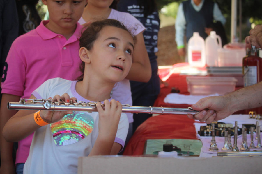 Seven-year-old Brianna Crozly learns how to play and hold a flute from a volunteer at the Instrument Petting Zoo.