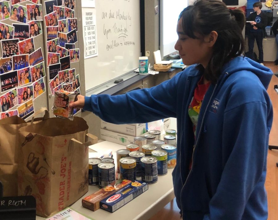 Sophomore+Valentina+Espinosa+puts+food+into+a+paper+bag+for+the+canned+food+drive.