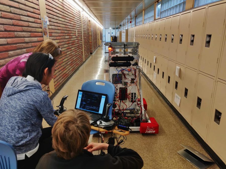 Two students and a mentor work on the robots  autonomous capabilities.