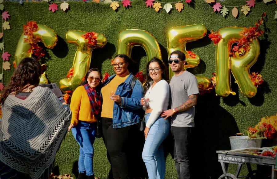Four friends enjoy the fall-themed photo opportunity at Cider Fest.