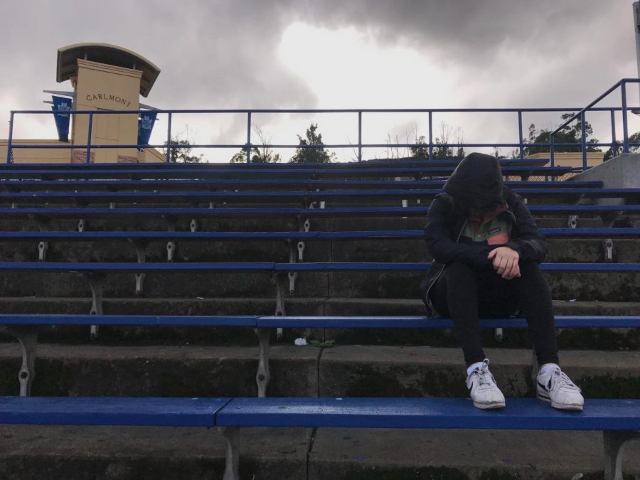 Student at Carlmont High School takes a break, and a moment to themselves, as they sit on the bleachers overlooking the field.