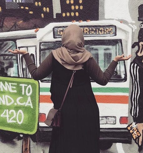 Matab Abdaljalil faces a mural in Oakland. Her headscarf and long dress in front of the marijuana reference represent the cultural mixing and differences she experienced when she first moved to the Bay Area in 2015.