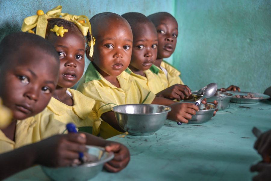 A group of malnourished children in Haiti eat a small meal together.