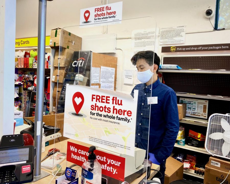 Joshua Sun, a junior and employee at CVS Pharmacy, checks a customer out while following the appropriate safety precautions. 