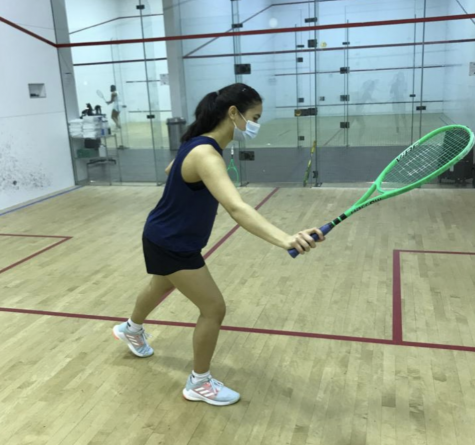 Aanika Tiwary raises her racket as she prepares to swing and hit the ball against the wall.