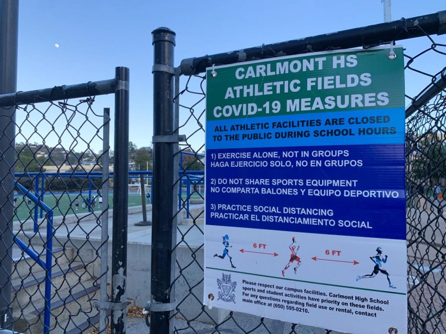 The gates to enter into the Carlmont football stadium display the COVID-19 field restrictions.