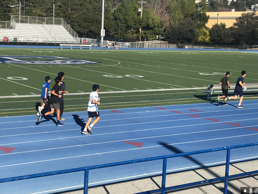 Carlmont cross country athletes run around the track as a team. 