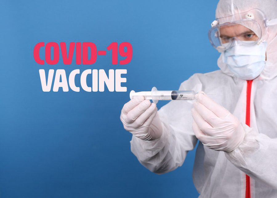 Doctor in face mask holding syringe with Covid-19 Vaccine text by focusonmore.com is licensed under CC BY 2.0